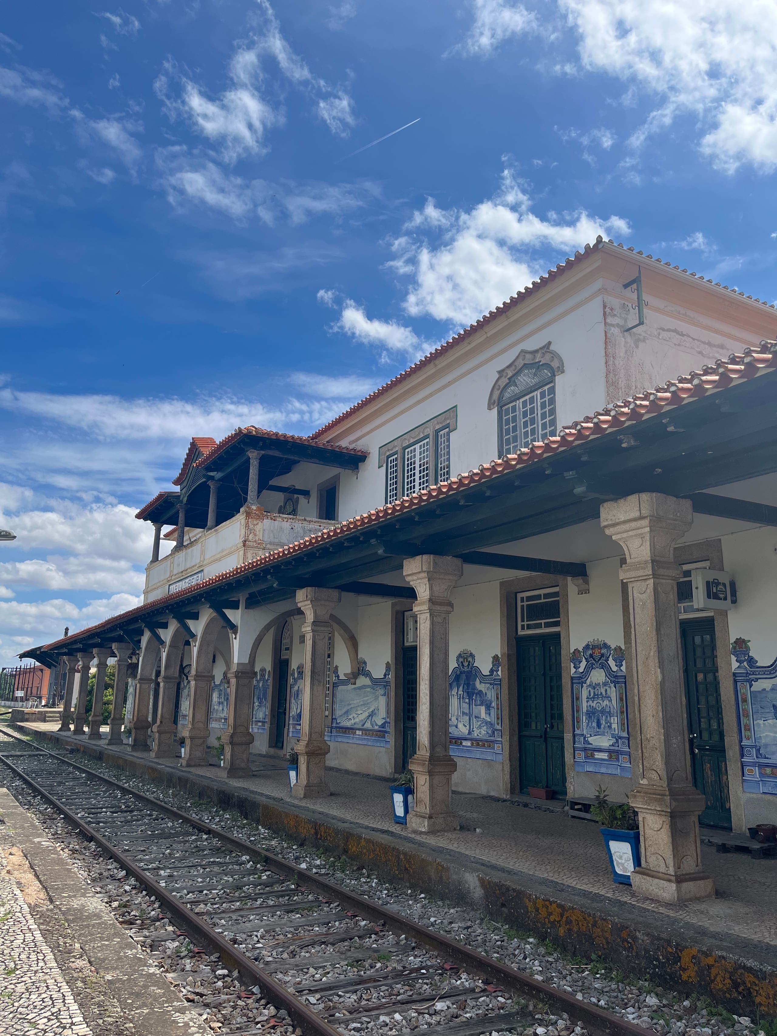 Historischer Bahnhof mit blauen Azulejo-Kacheln und Bogengang unter blauem Himmel