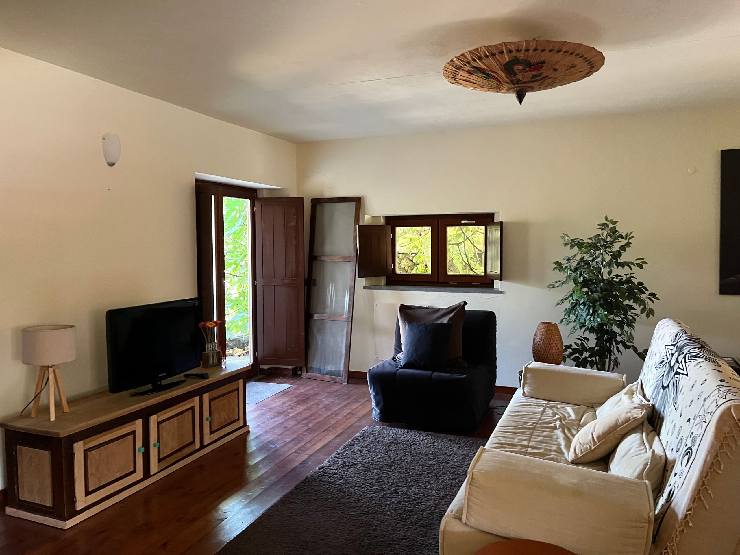Gemütliches Wohnzimmer mit Sofa, Sessel, Fernseher und Holzkommode.