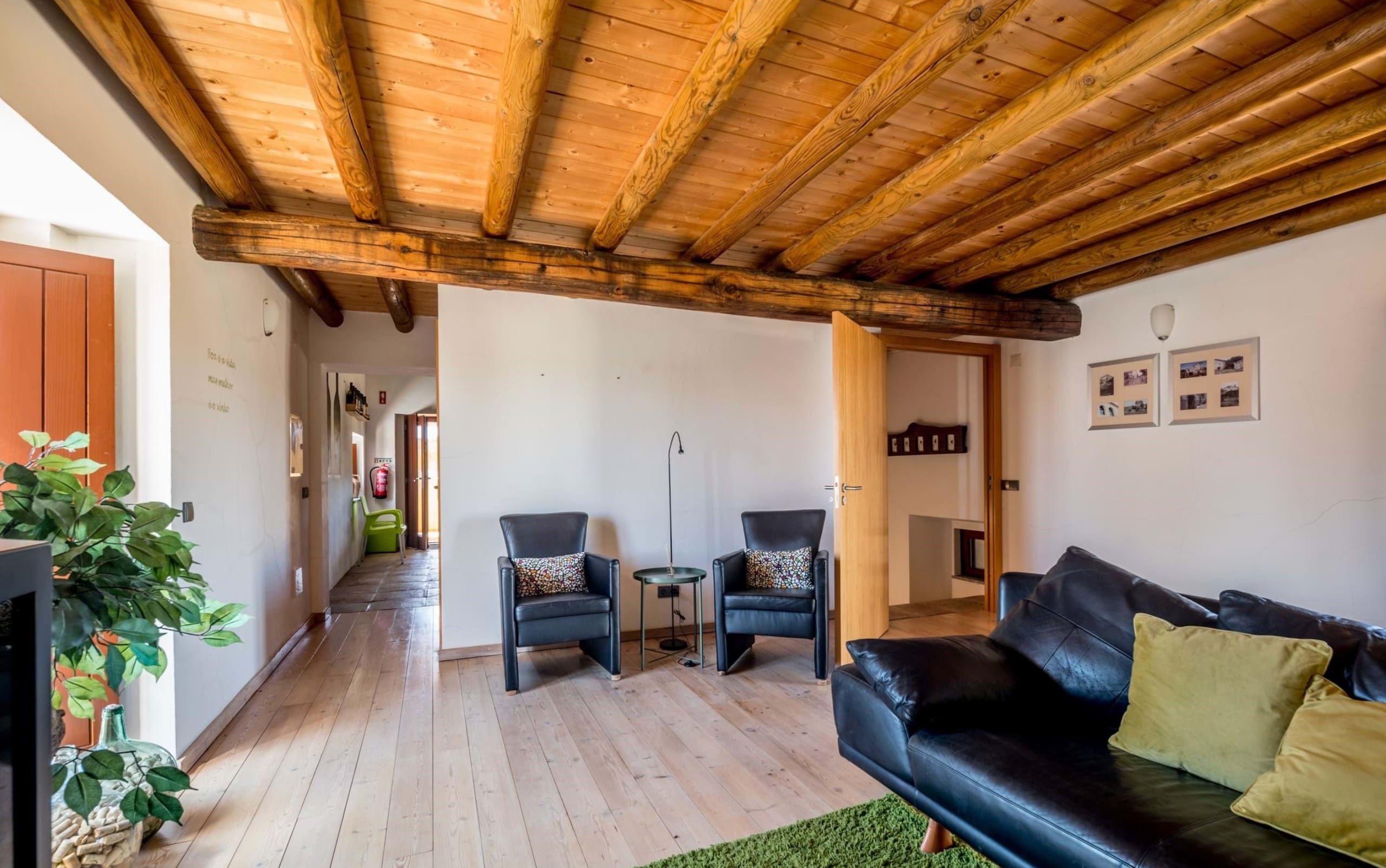 Wohnzimmer mit Ledersofa, Sesseln und rustikaler Holzbalkendecke