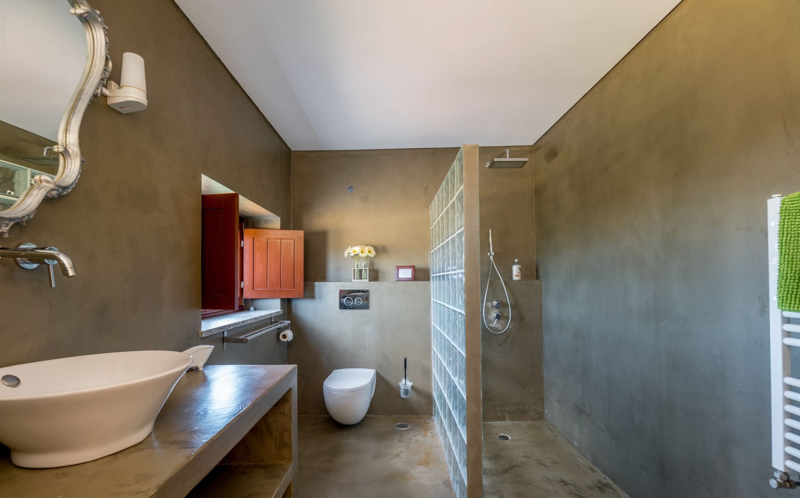 Badezimmer mit ovalem Aufsatzwaschbecken, Glasbausteinwand und offener Dusche.