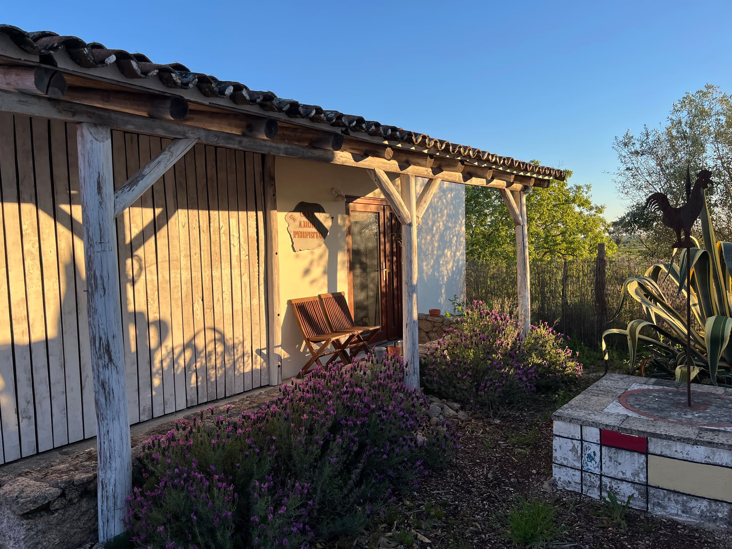 Hofgebäude mit Holzläden und überdachter Veranda im warmen Abendlicht.