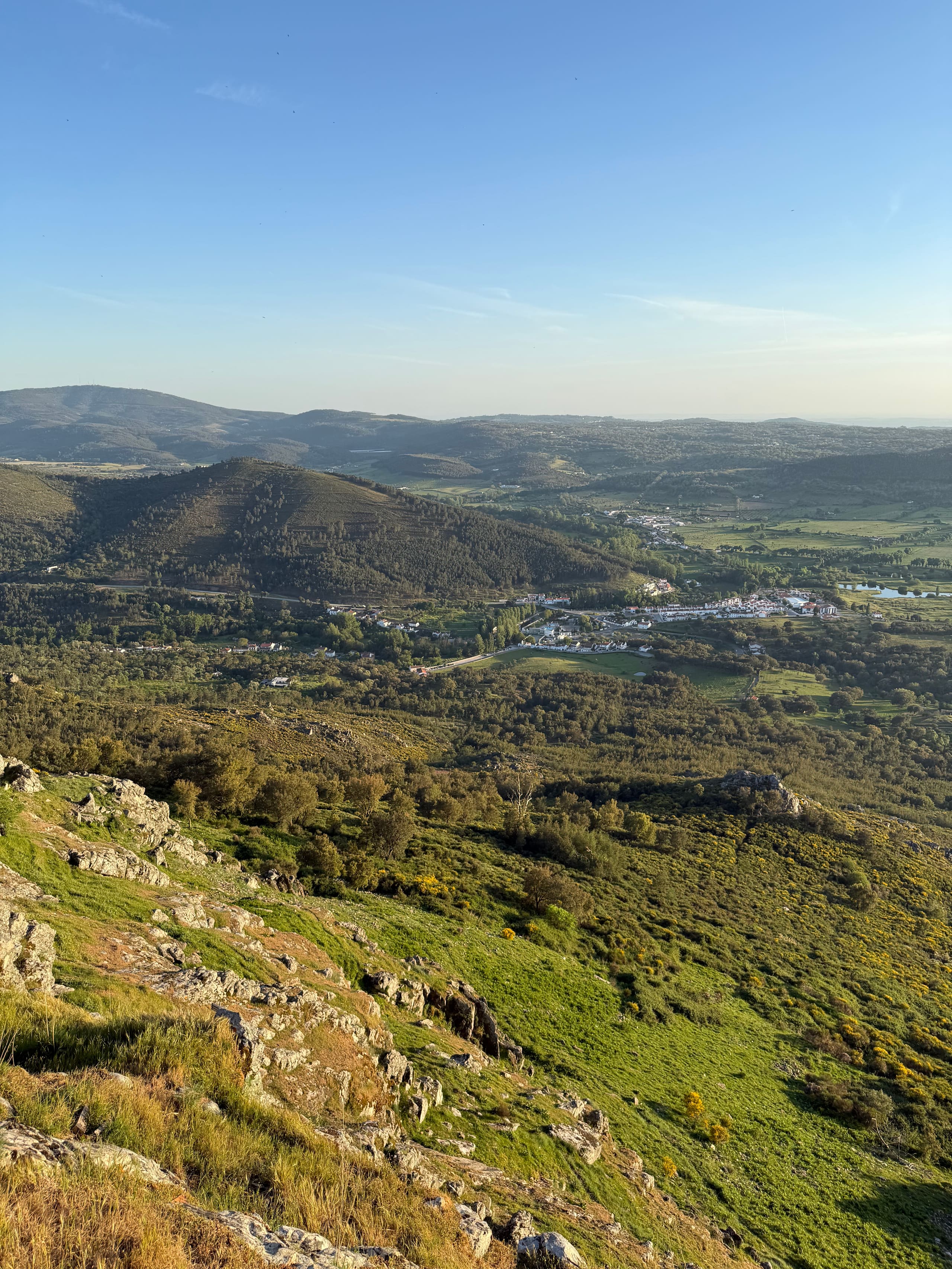 Weiter Blick über Hügellandschaft und ein kleines Dorf im Abendlicht
