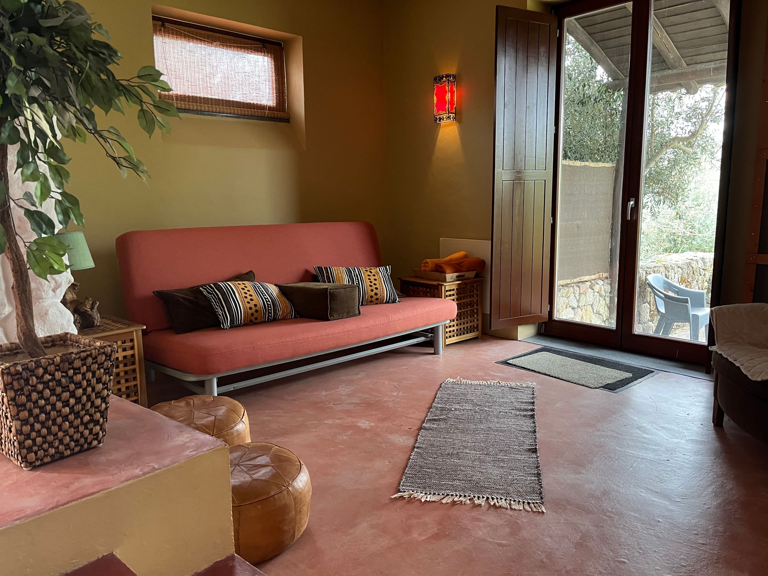 Wohnzimmer in Terrakottatönen mit rosafarbenem Sofa und Zugang zur Terrasse.